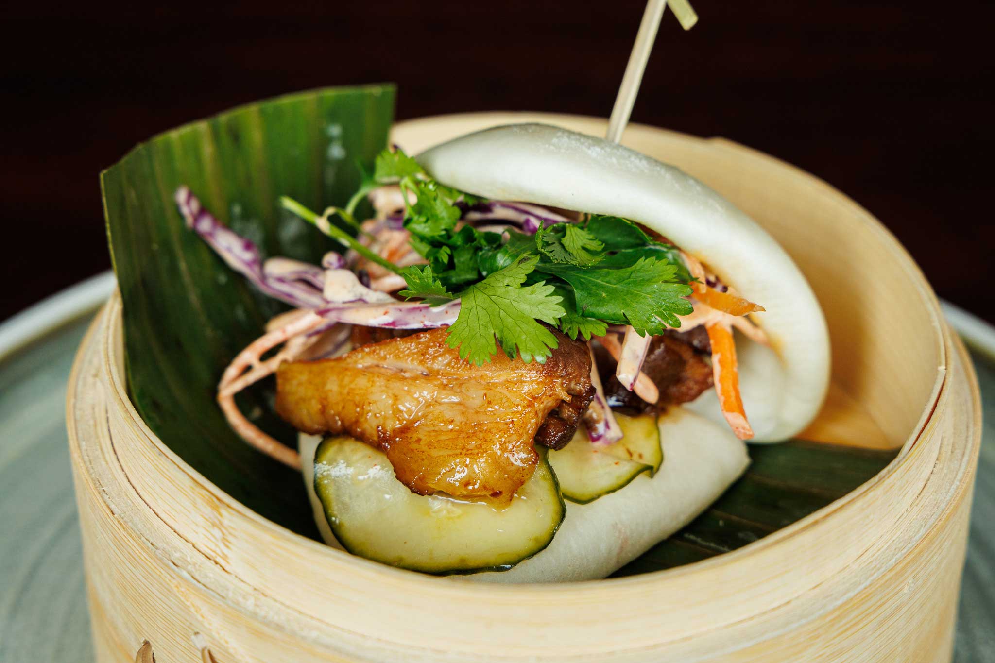 A single pork belly bao with pickled vegetables and cilantro