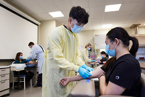 A medical assistant taking a patient's blood in a lab