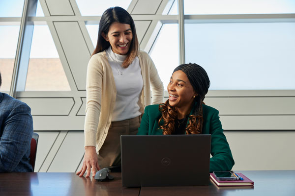 Two people discussing while looking at an open laptop