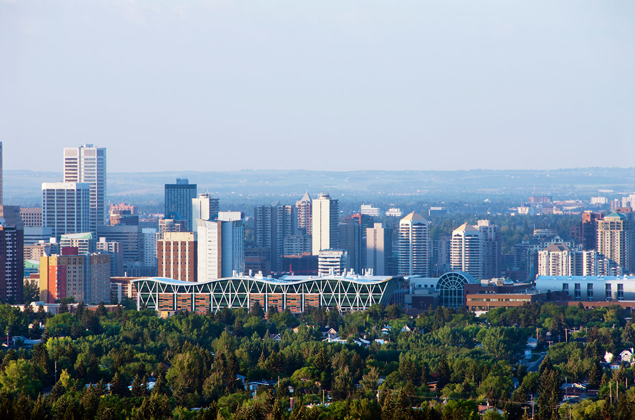 A panoramic view of a city skyline with a mix of modern skyscrapers and green spaces.