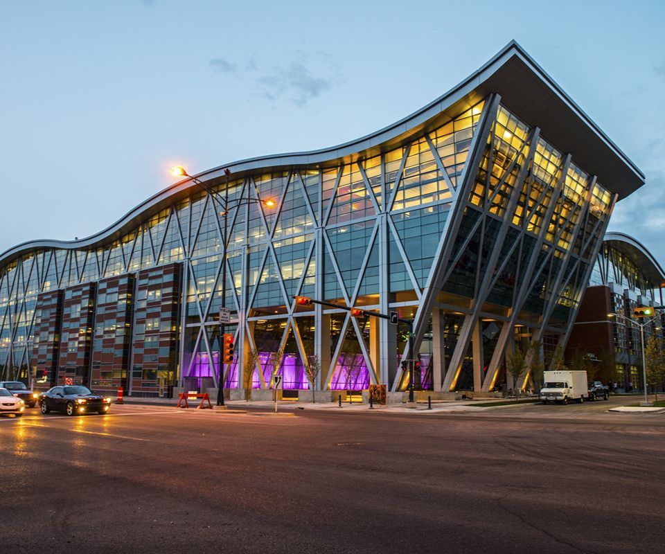 A modern glass-and-steel building with a sweeping curved roof and diagonal support columns.