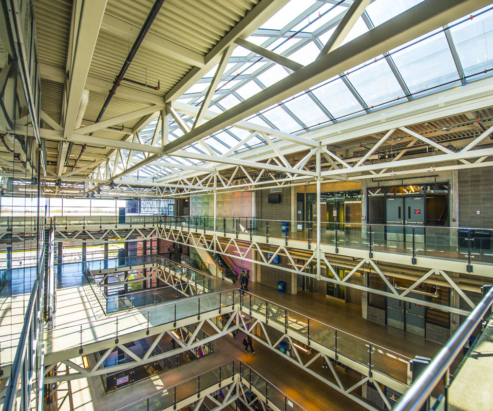 Interior view of the modern Aldred Centre atrium showcasing an open layout with glass ceilings and steel support beams.