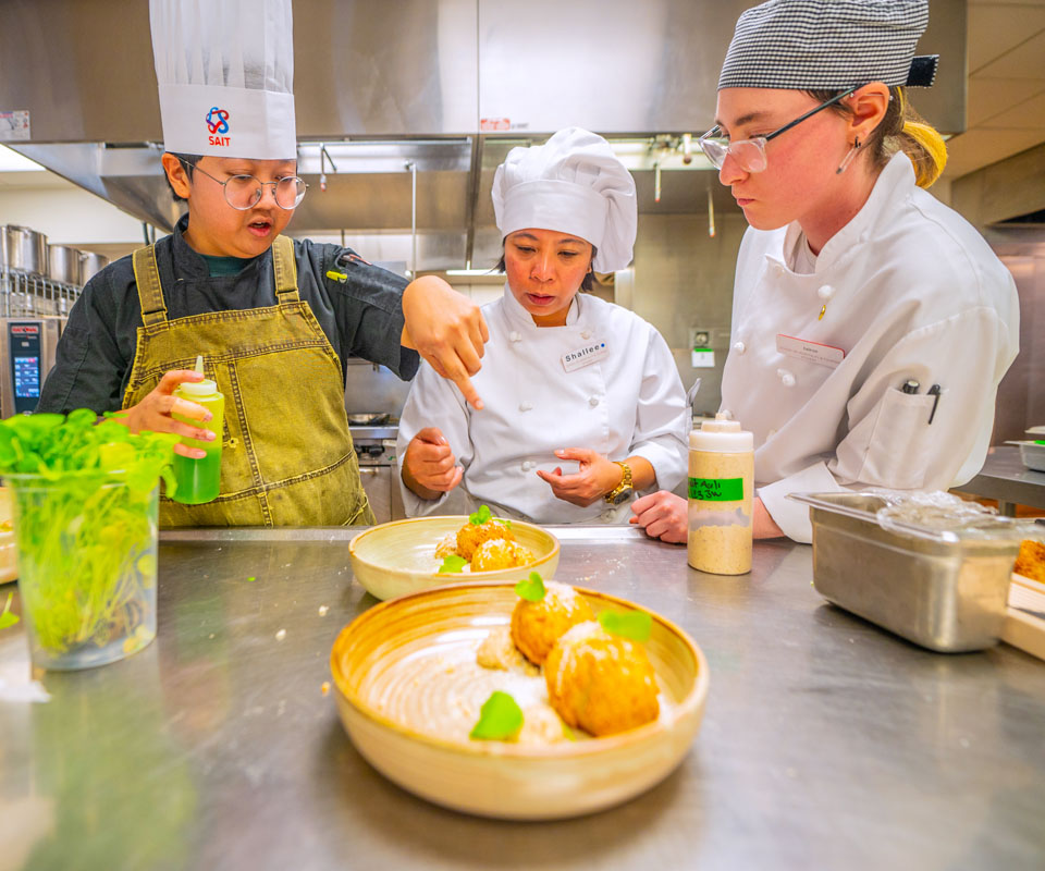 Culinary students collaborating in a kitchen, discussing plating techniques for a gourmet dish.