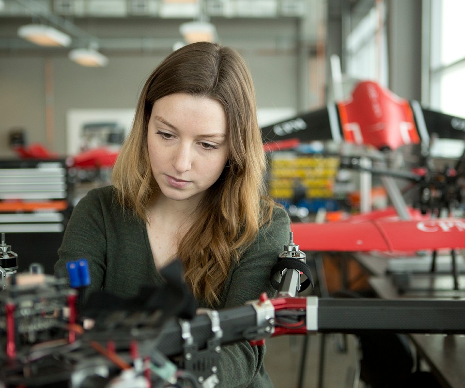 A woman working on a drone in a modern workshop environment.
