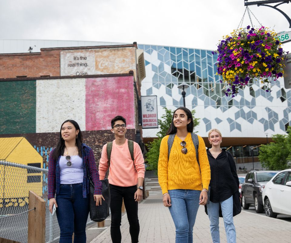 four students walking by colorful building