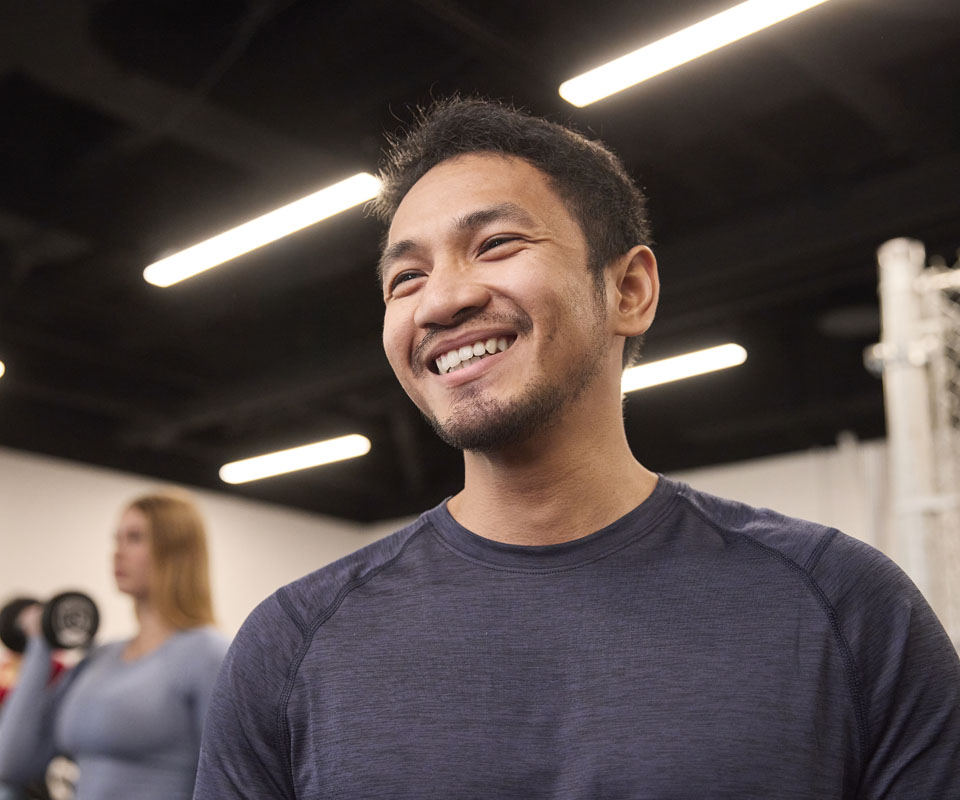 A smiling man in workout attire, showcasing a positive and enthusiastic attitude in a gym setting.
