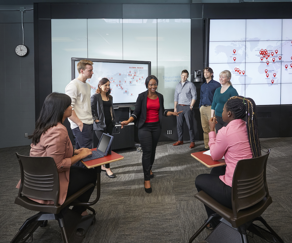 Seven people in a conference room viewing a presentation