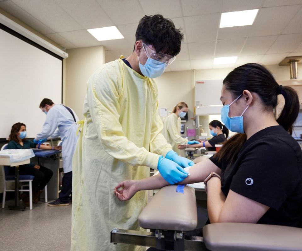 medical student prepares to draw blood from patient