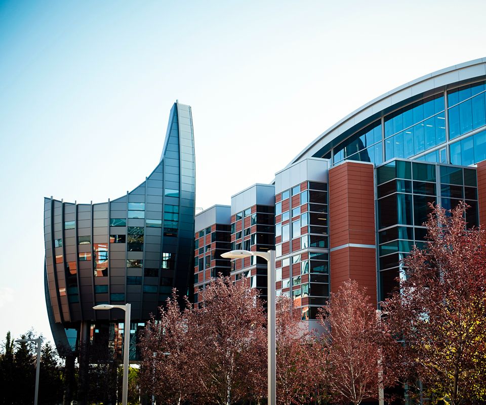 Modern multi-story academic building with curved glass and brick facades.