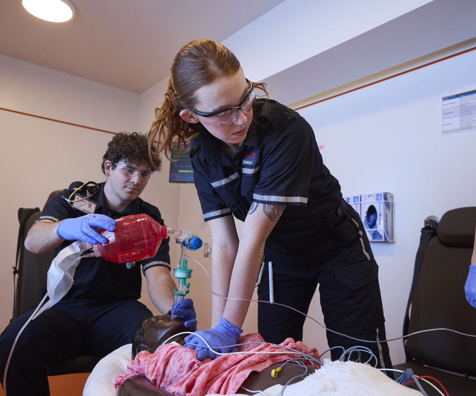 Paramedic students performing CPR on a practice patient in a clinical setting.