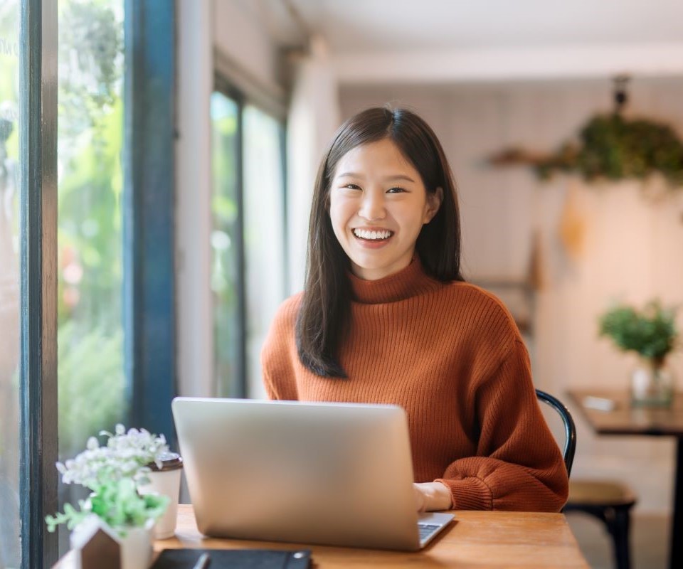 smiling student in brown sweater using laptop