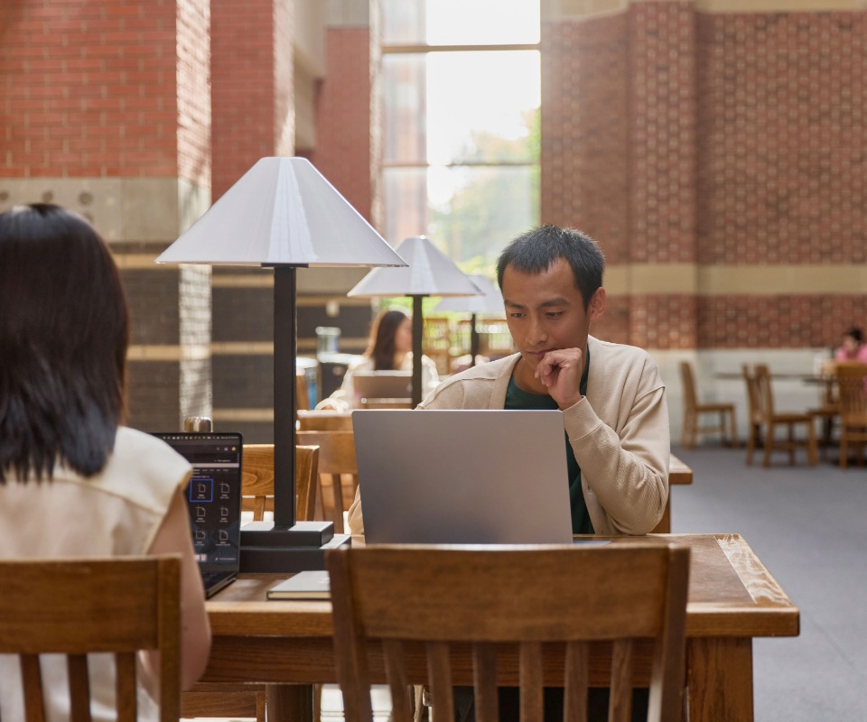 A woman works on a laptop with a cup of coffee beside her.
