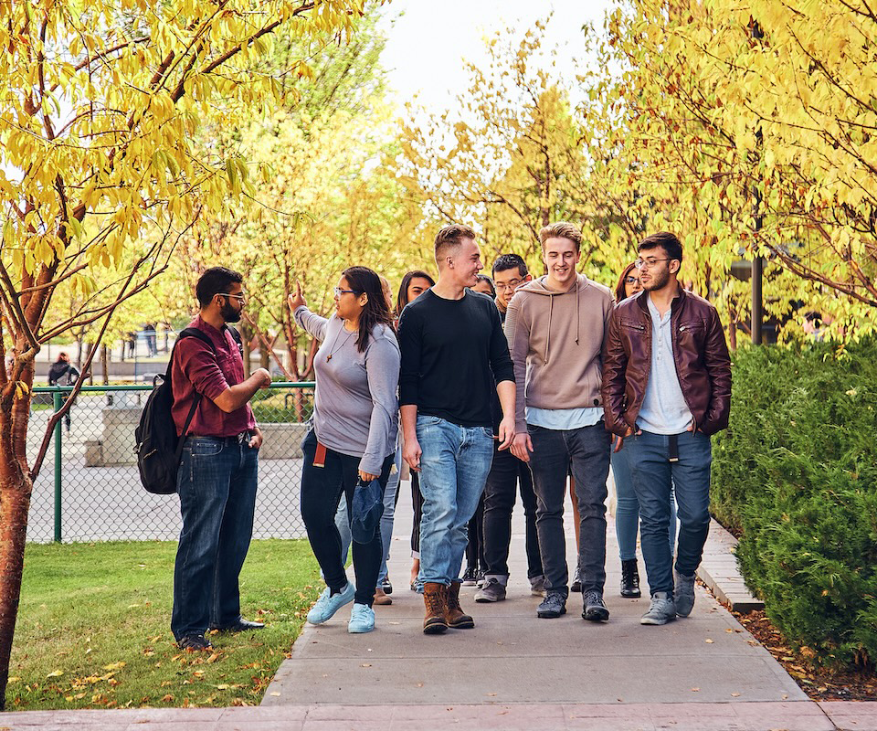 A group of SAIT students walk outside Heritage Hall in the autumn.