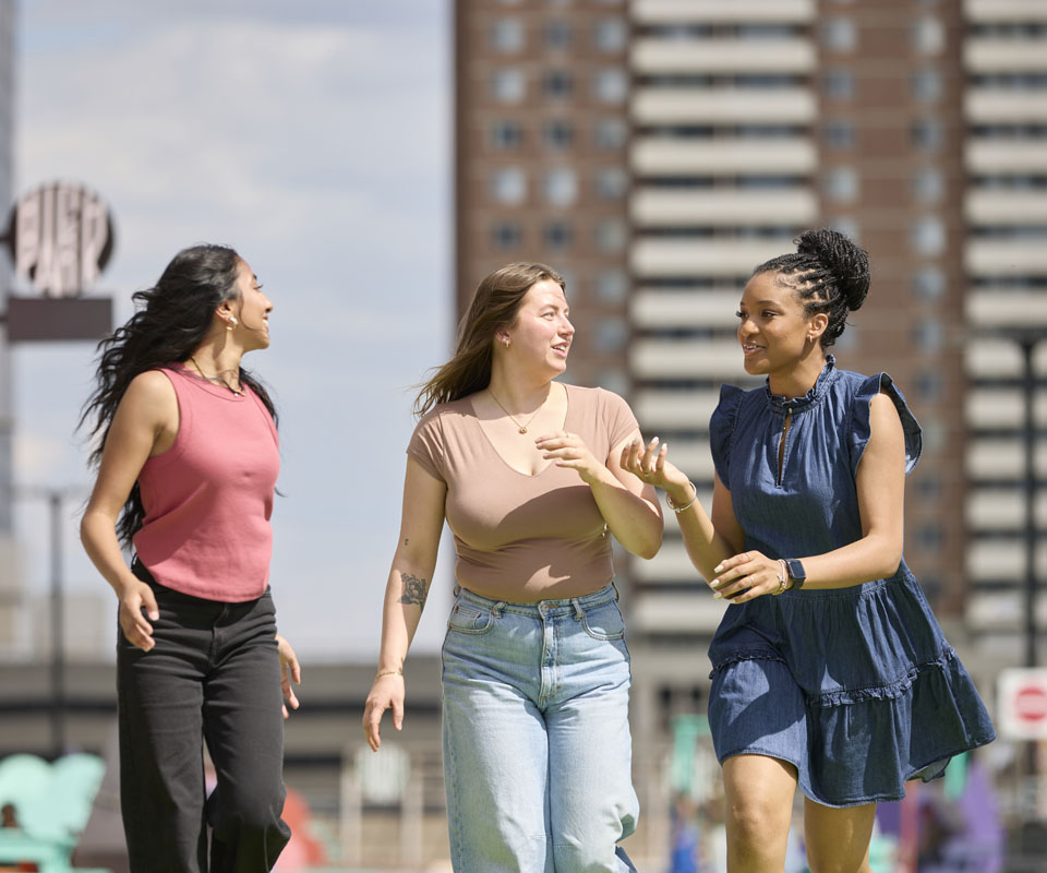 Three diverse young women walking together and enjoying a sunny day outdoors in downtown Calgary.