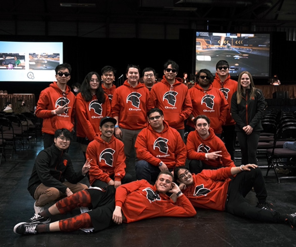 Group photo of the Trojans eSports team, wearing matching hoodies and smiling at the camera