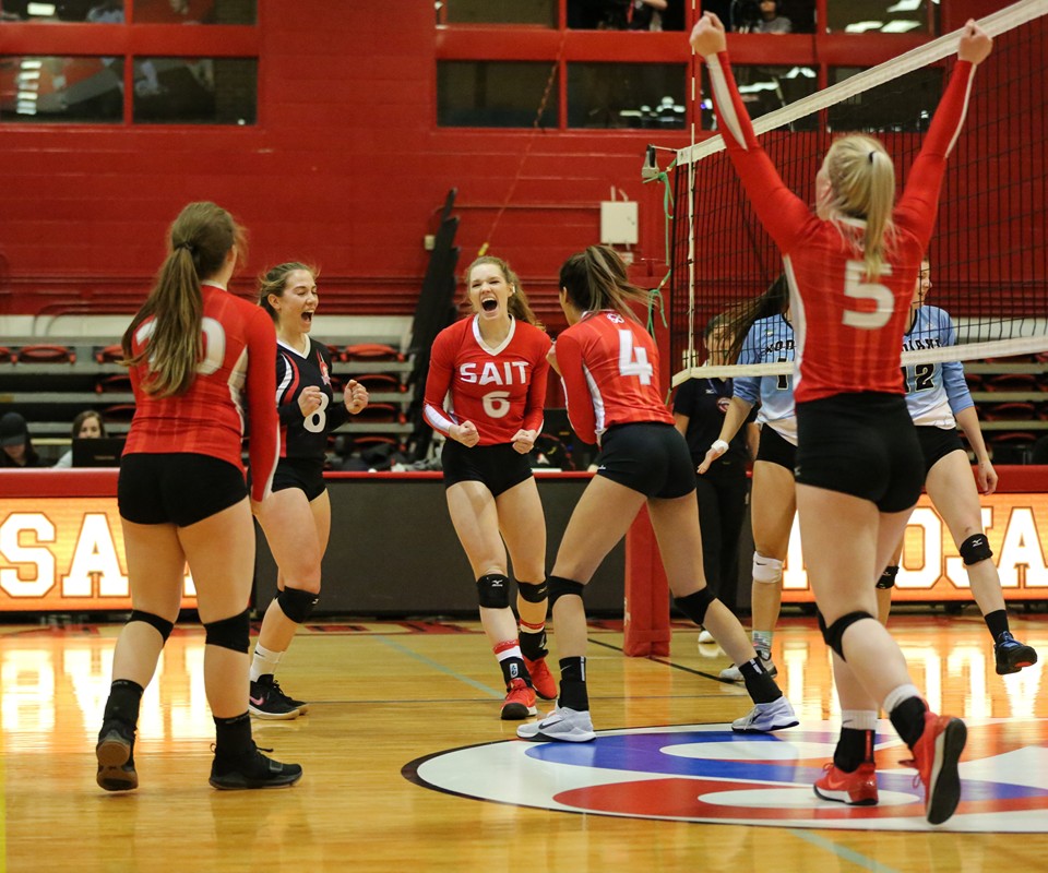 The Trojans women's volleyball team celebrating at a volleyball game.