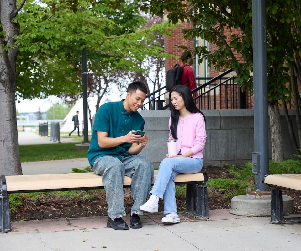 Two students sitting outside on a bench