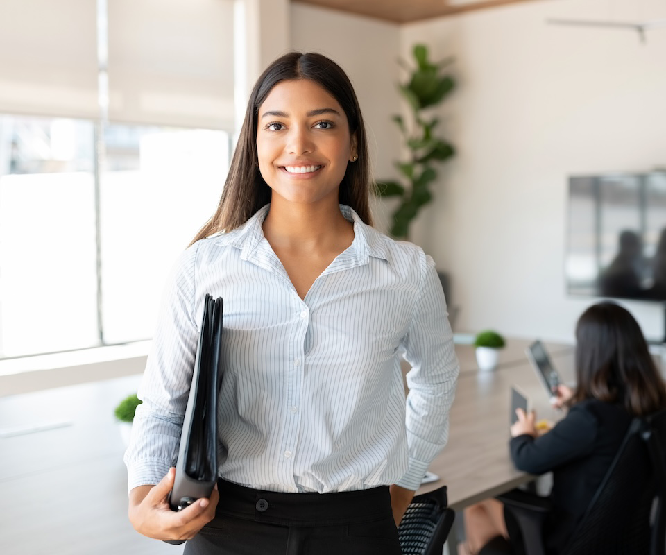 Woman holding clipboard smiling in a meeting room