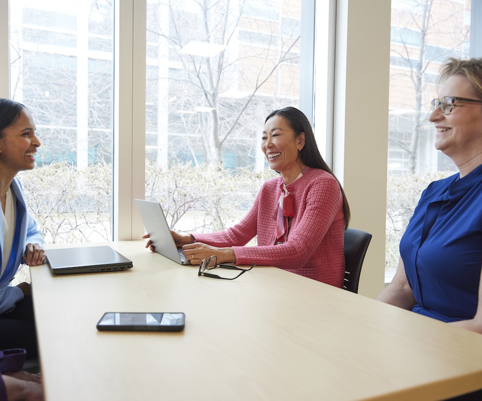 Three colleagues collaborating around a table in a bright meeting room