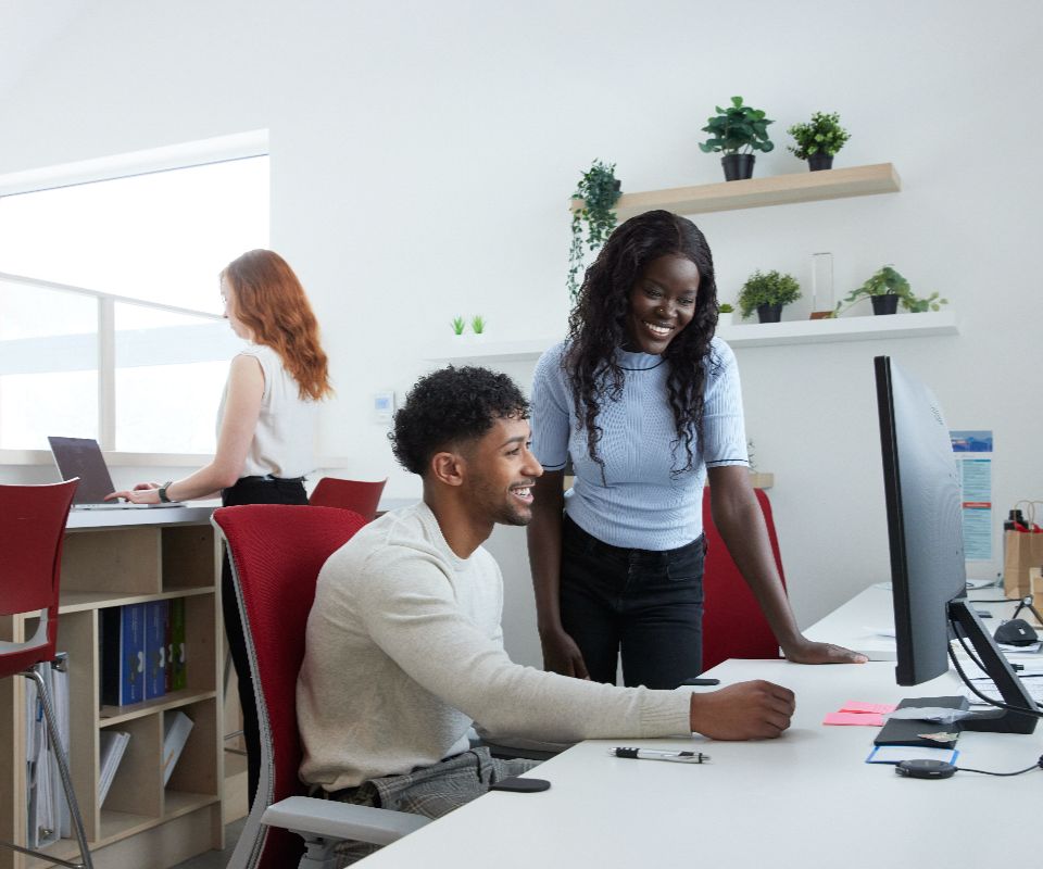 woman standing and man sitting at screen