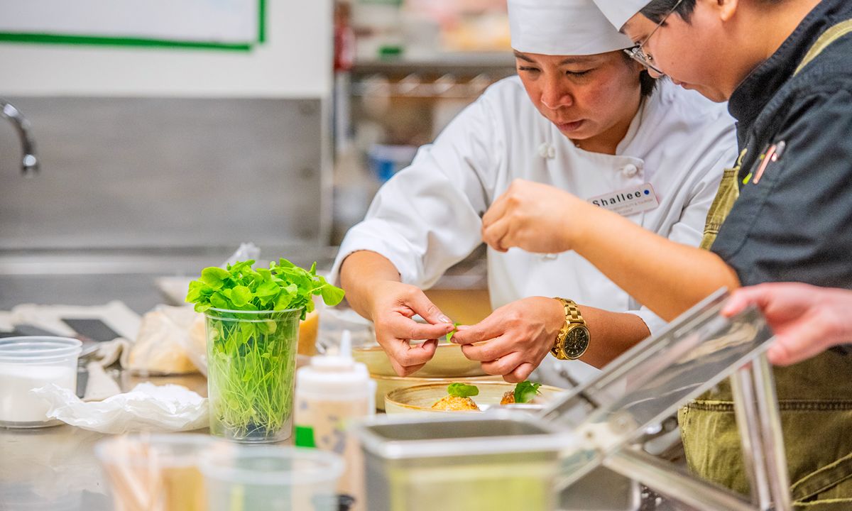 chefs collaborating on dish in professional kitchen