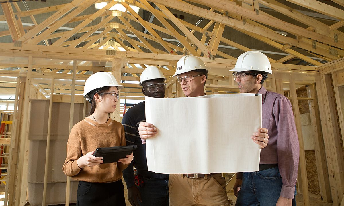 construction workers reviewing blueprints at wooden frame site
