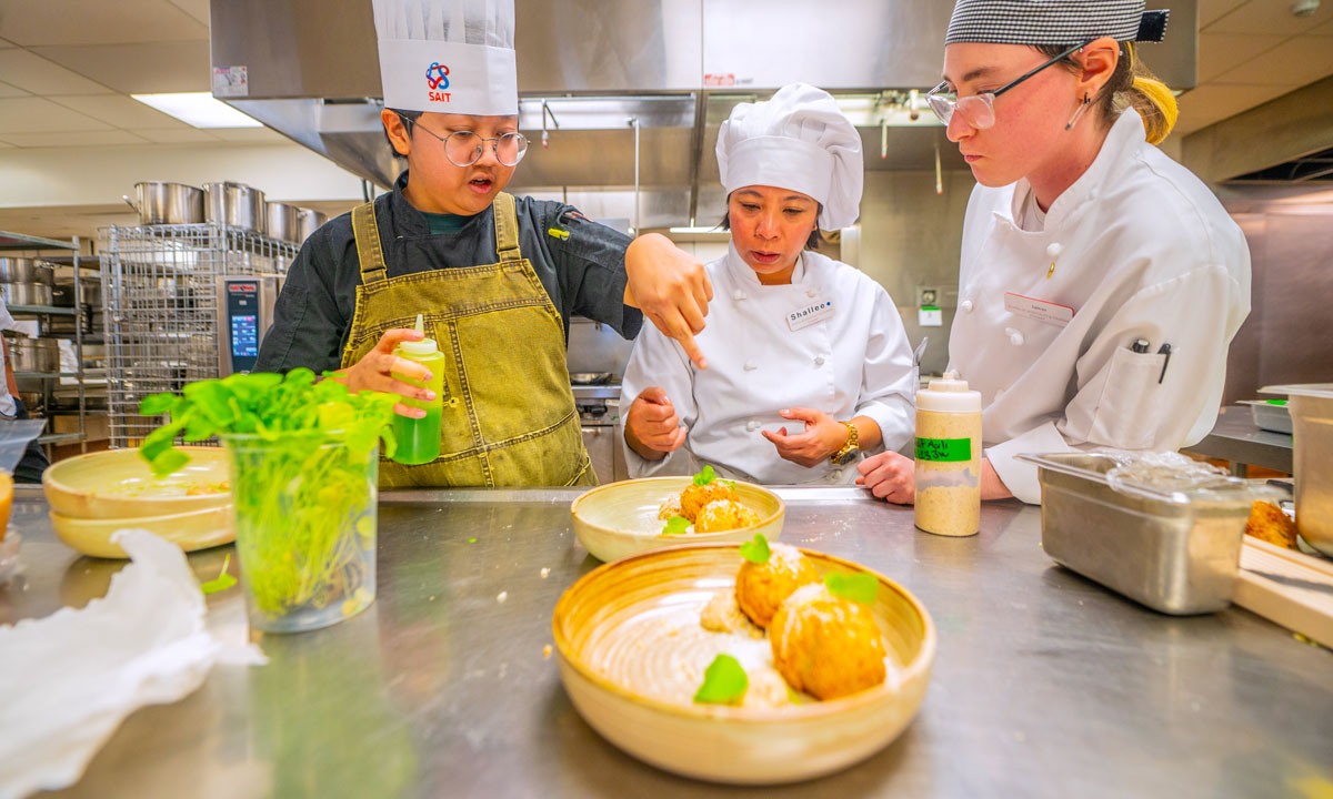 Students and instructors collaborate in a professional kitchen, plating dishes with attention to detail.