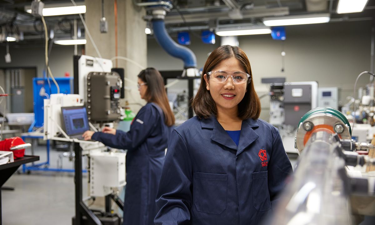 girl in blue lab coat and goggles working in lab