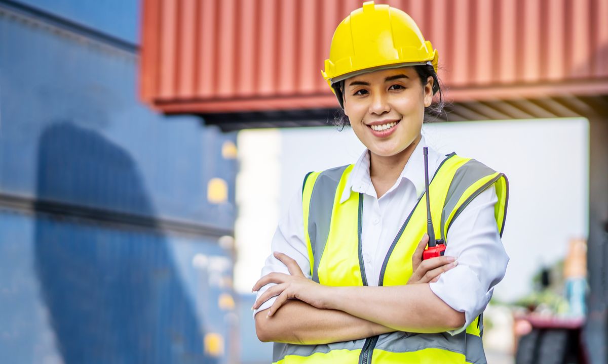 girl in safety vest and hard hat smiling at camera