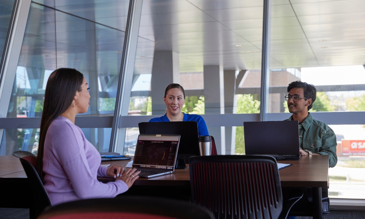 A group of students study by a window, smiling.