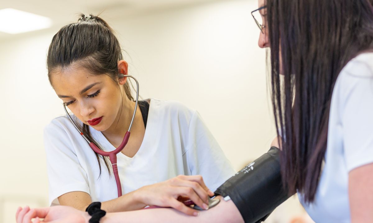 healthcare worker checking blood pressure with stethoscope