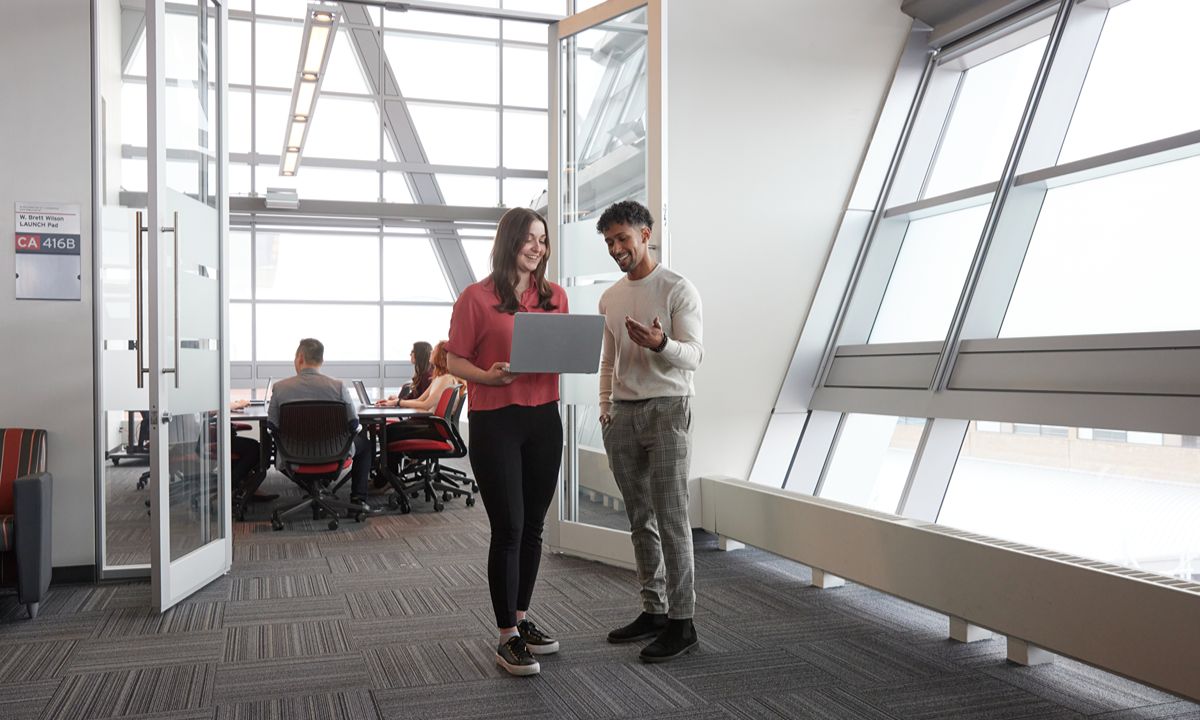 man and woman standing looking at laptop
