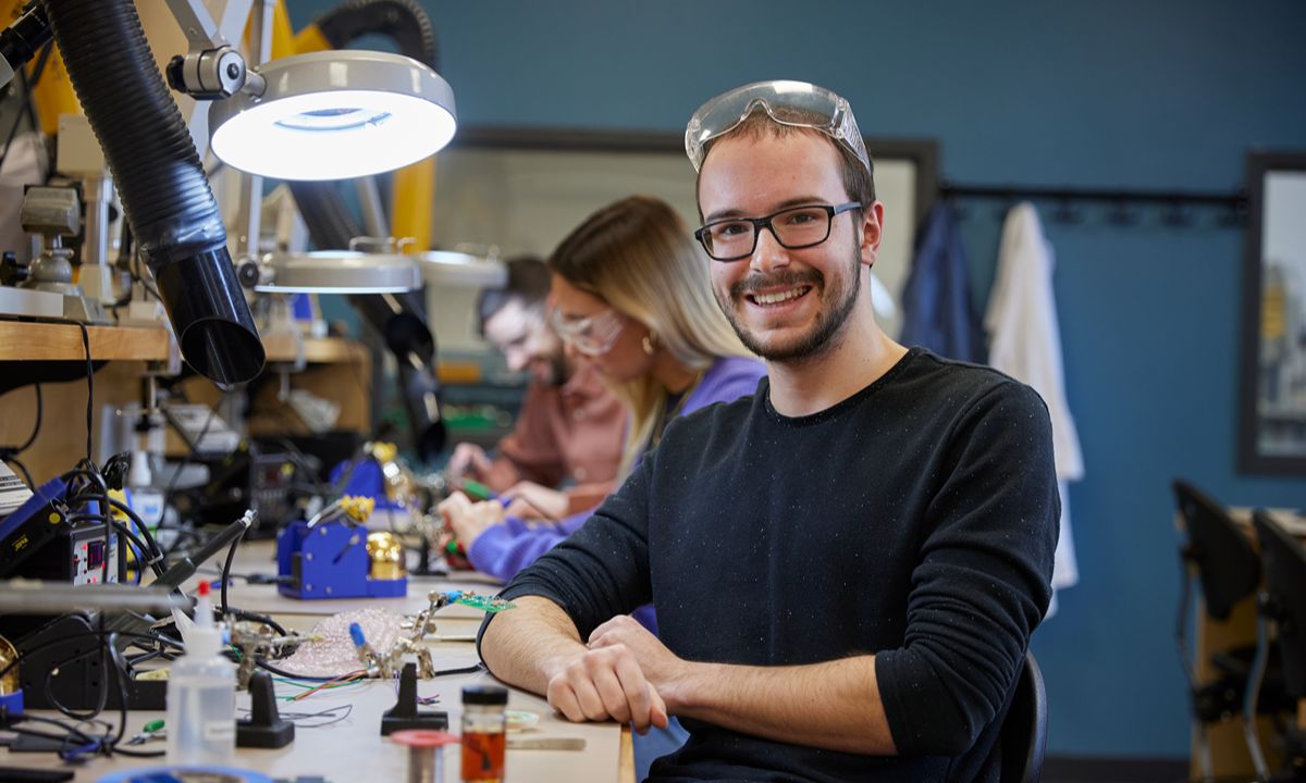 man in lab with safety goggles smiling at camera