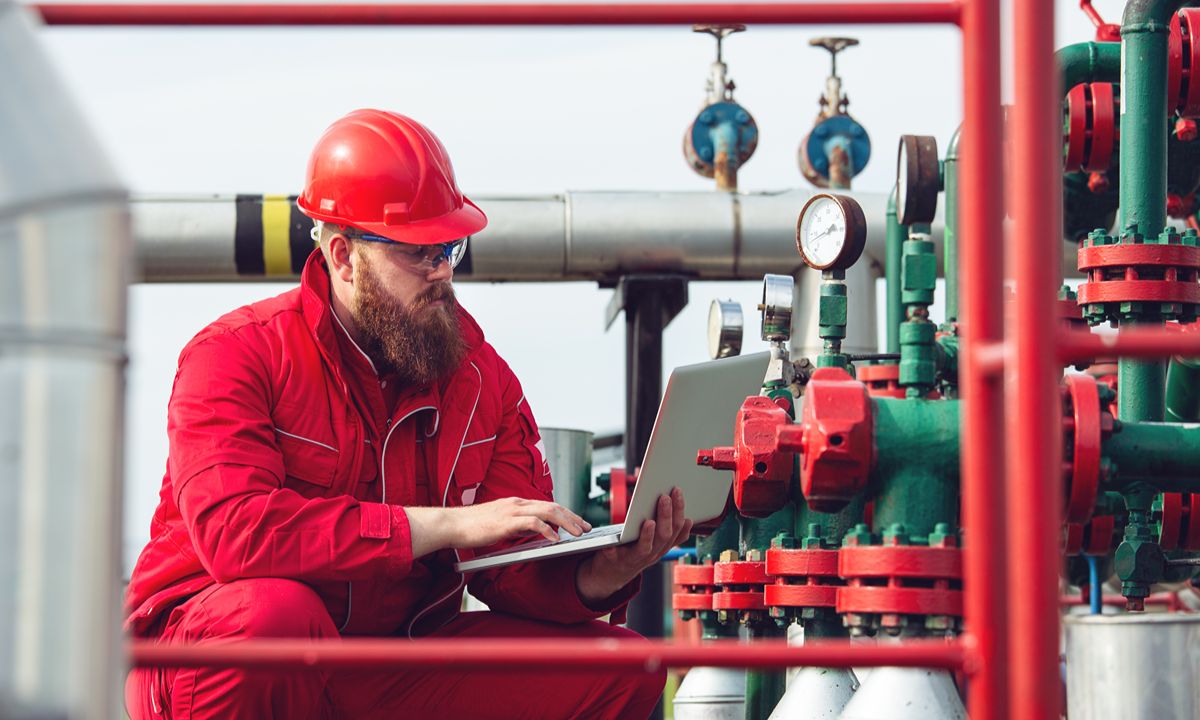 man in red hard hat working on laptop outdoors