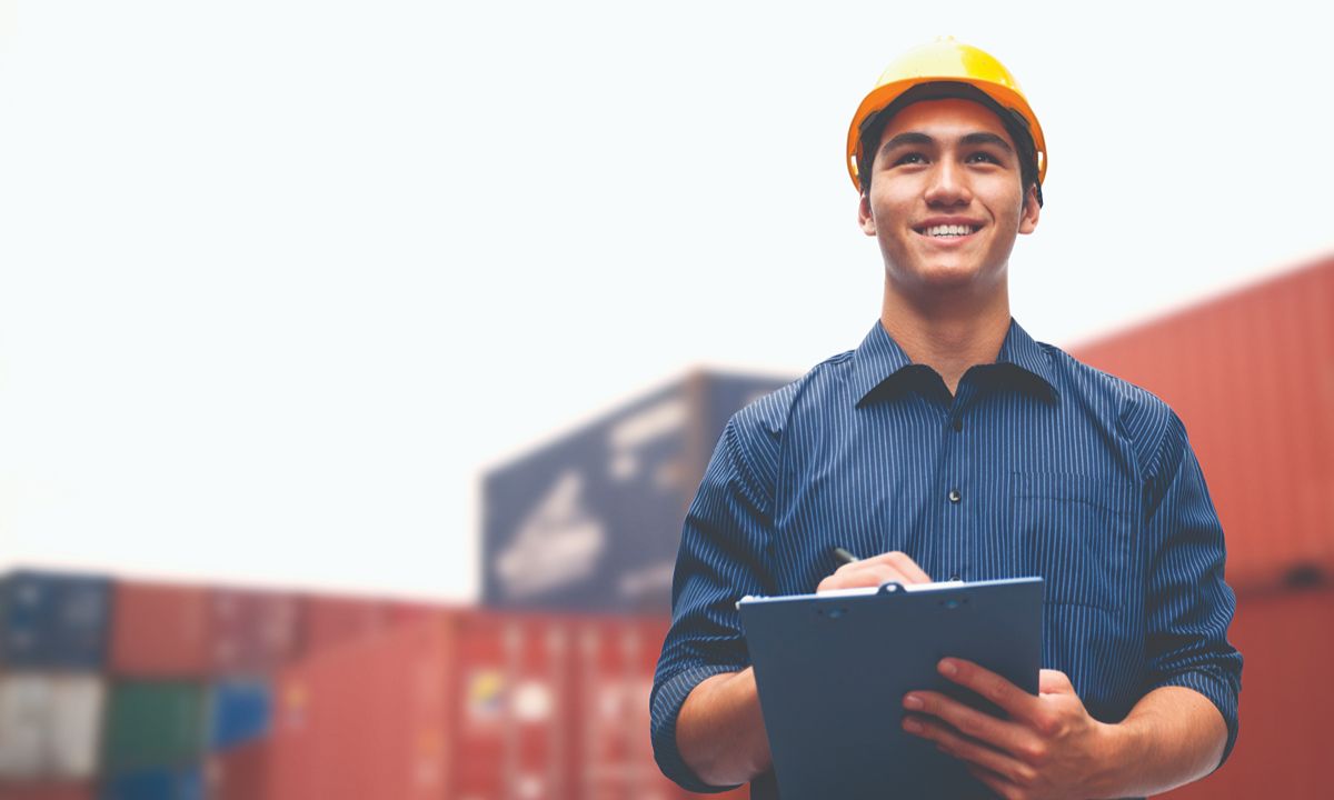 person in hard hat holding clipboard at shipping yard