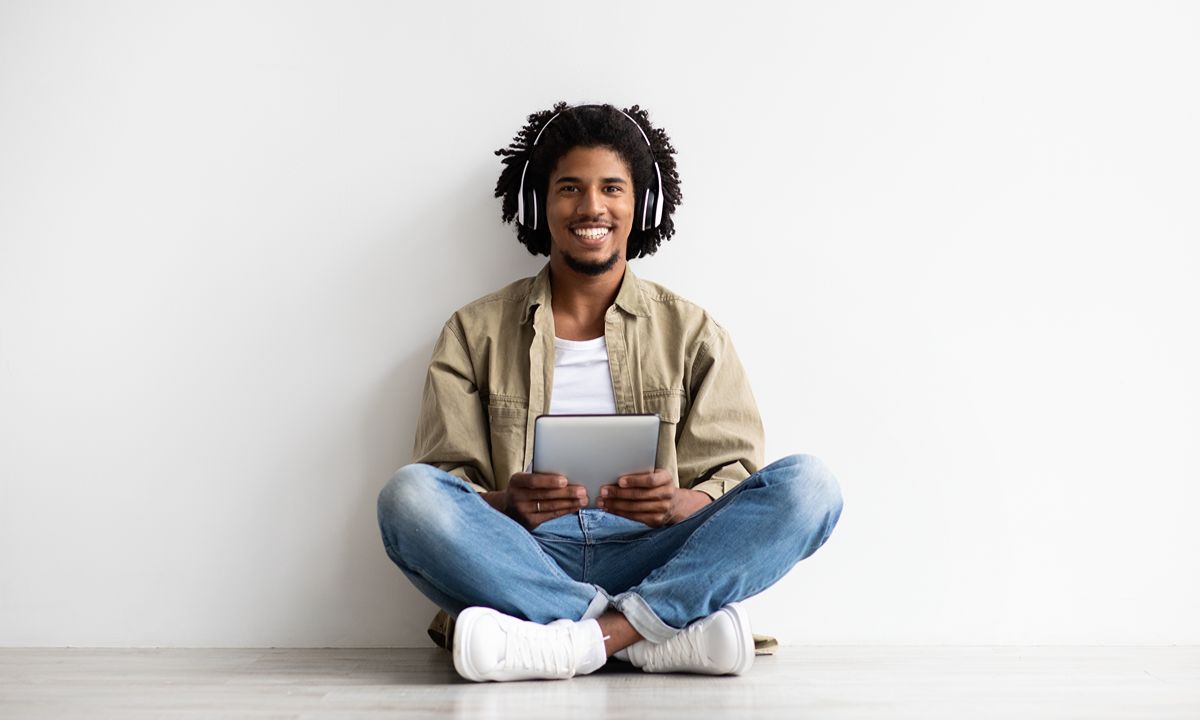 person sitting on floor using tablet with headphones