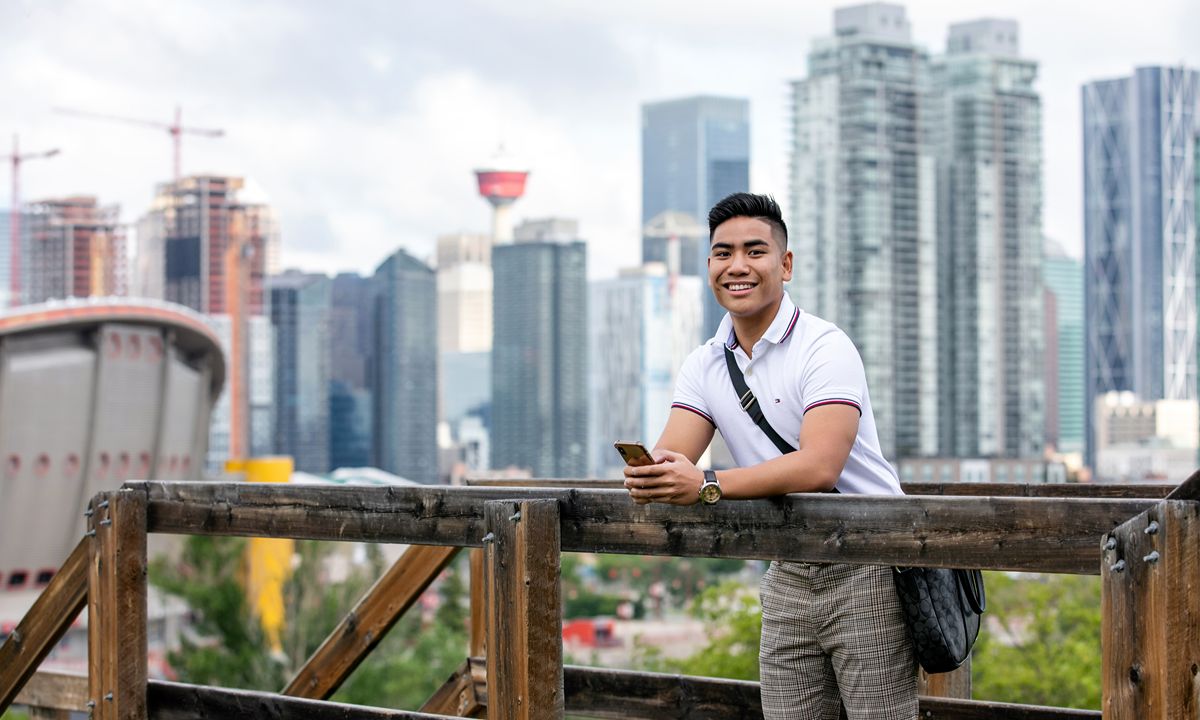 person smiling on bridge with smartphone