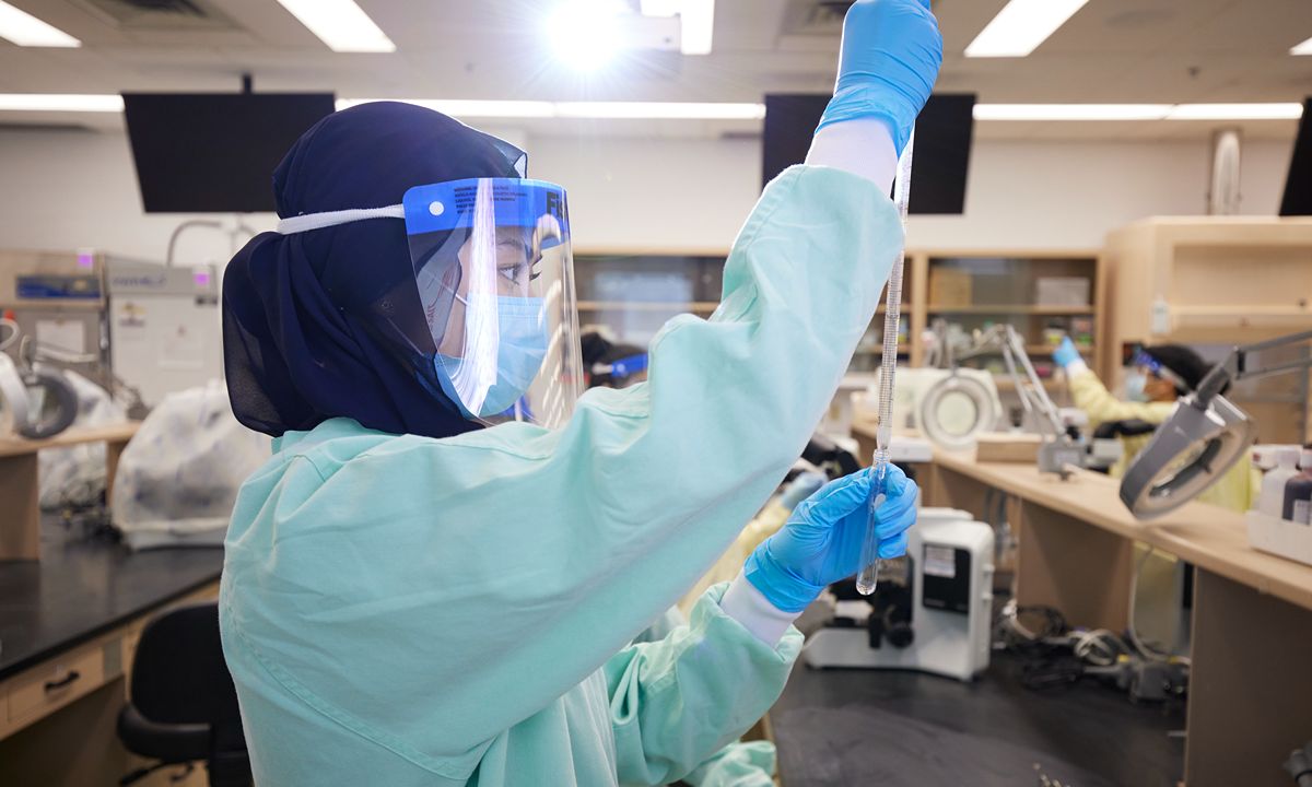 scientist using pipette in lab with protective gear