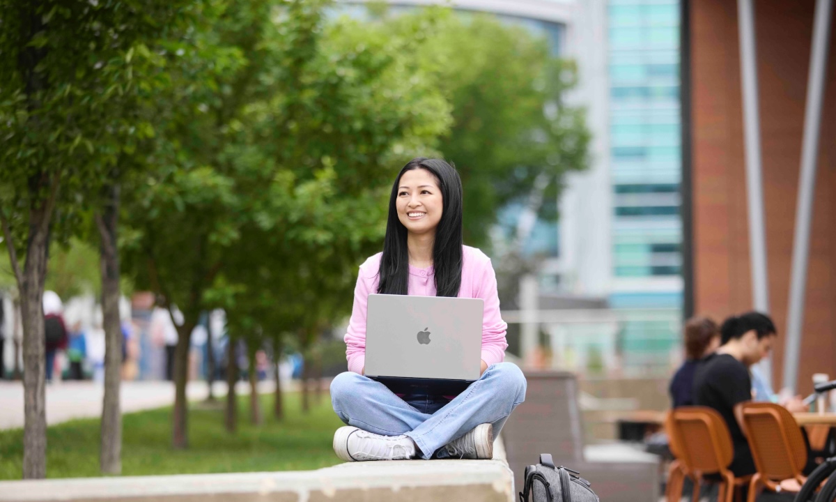 student sitting cross legged outside summertime