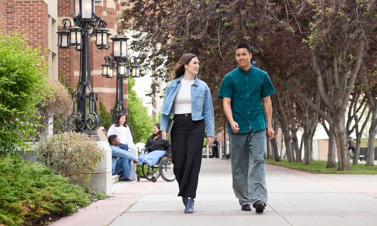 Two students walking on campus in front of Heritage Hall