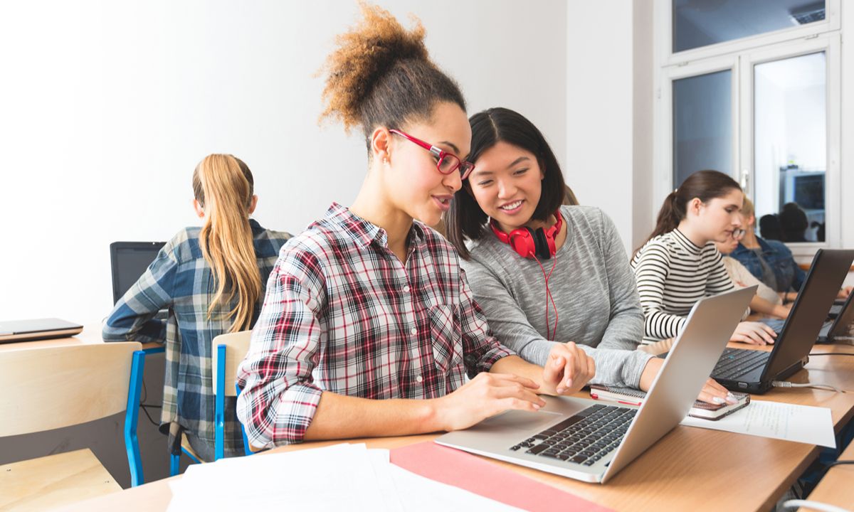 two students with headphones viewing screen in classroom