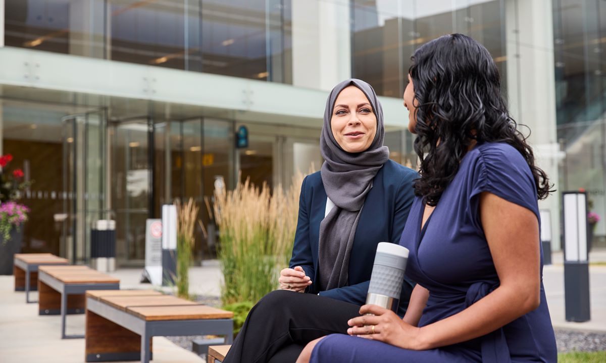 two women chatting on campus bench