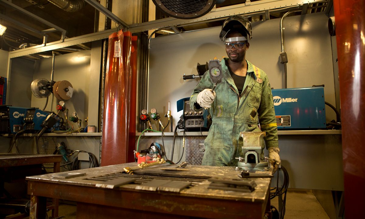 welder working in metal shop with tools and machinery