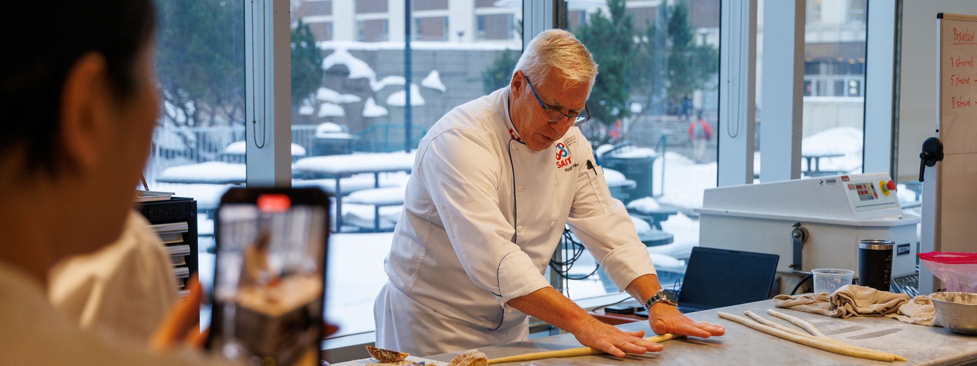 chef demonstrating dough rolling filmed on smartphone