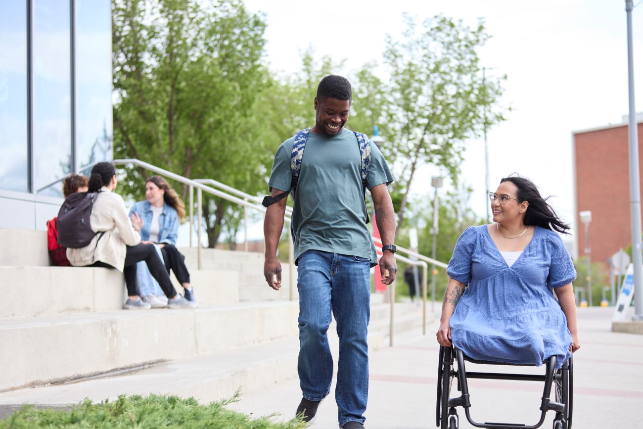 A man walking next to a woman in a wheelchair