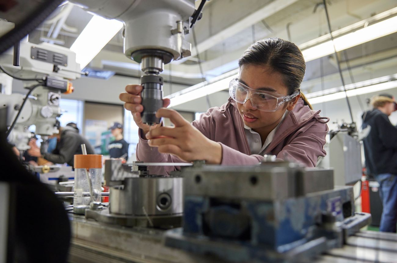 Person operating a milling machine in a workshop setting.