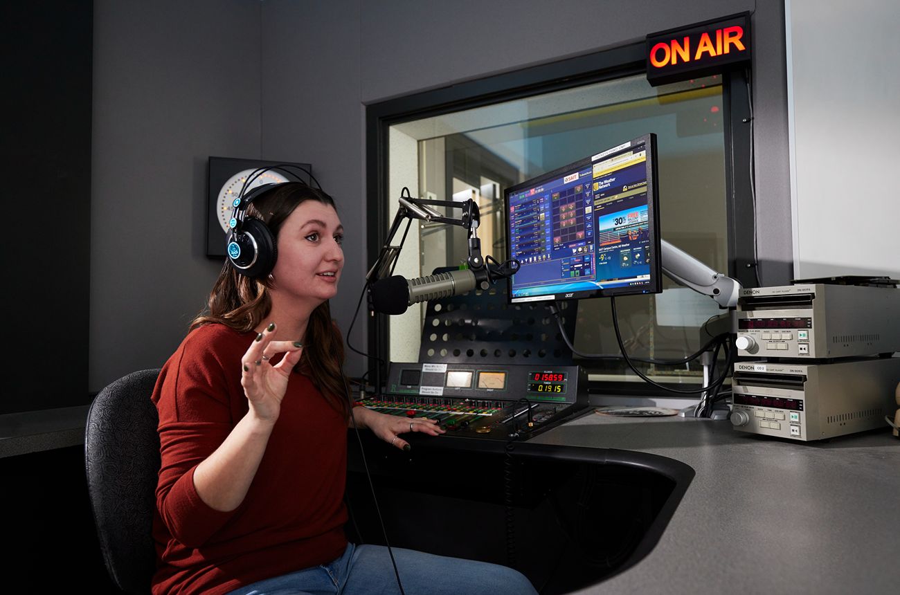 Radio host speaking into a microphone in a studio.