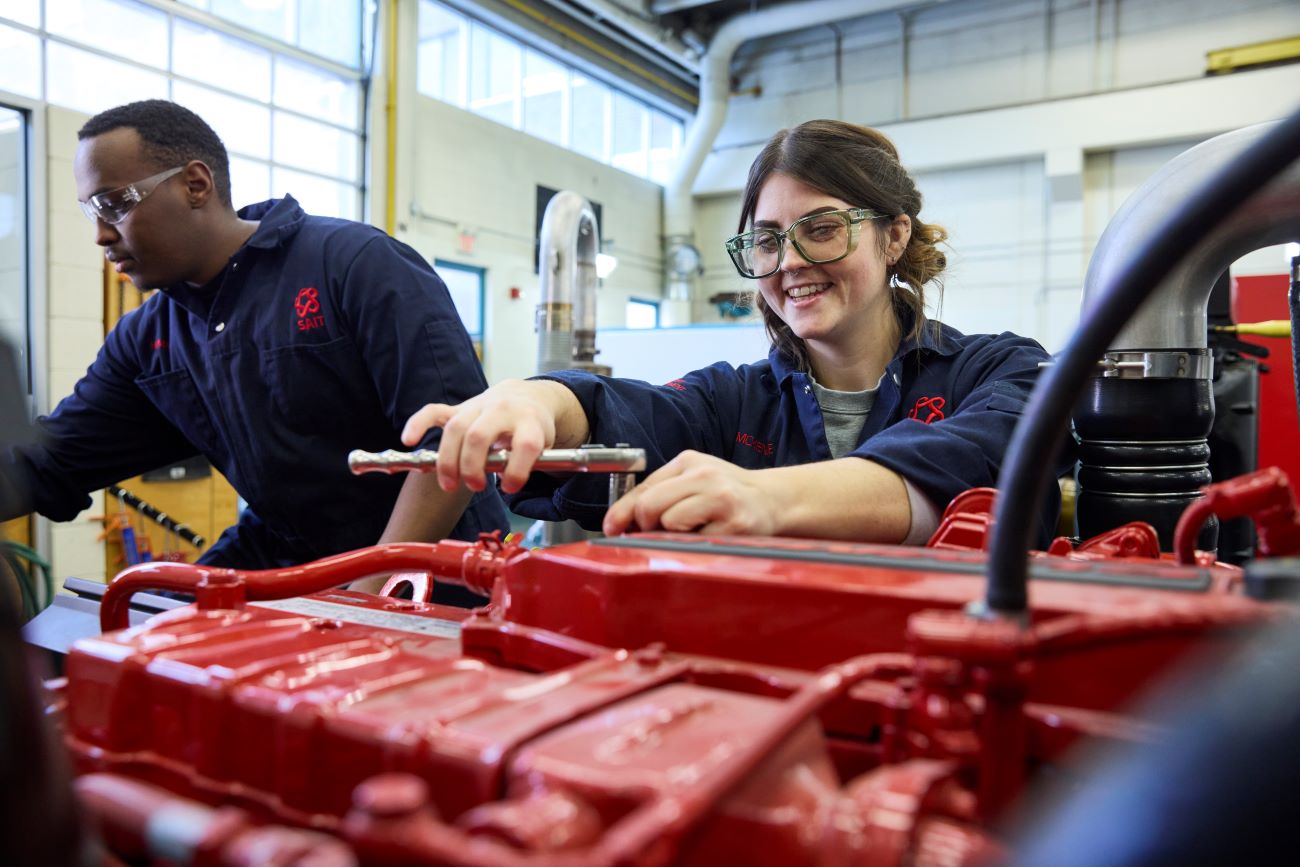 Two students wearing safety equipment work together in a lab