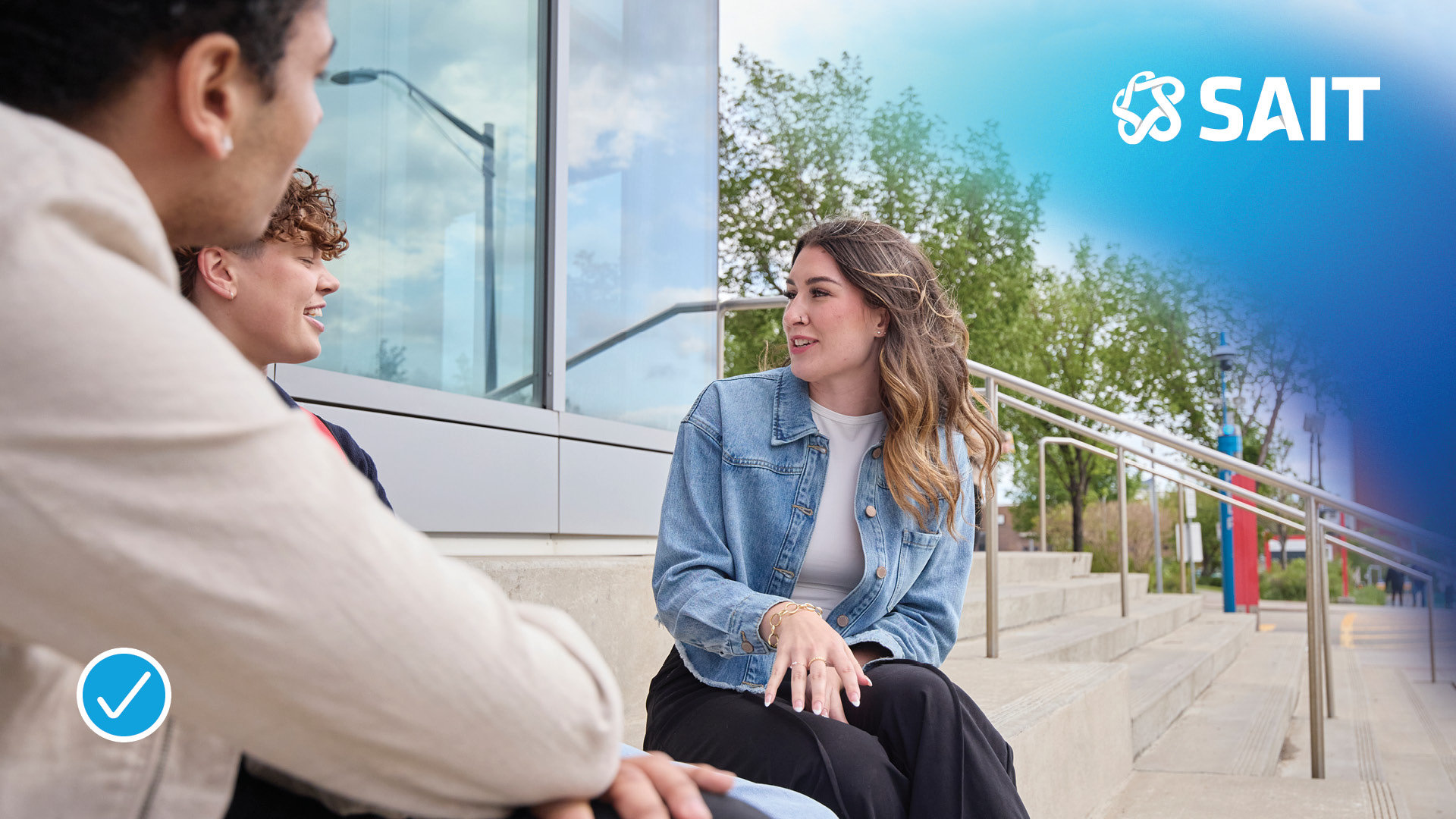 Group of three students engaged in conversation outdoors, with the SAIT logo in the top right corner.