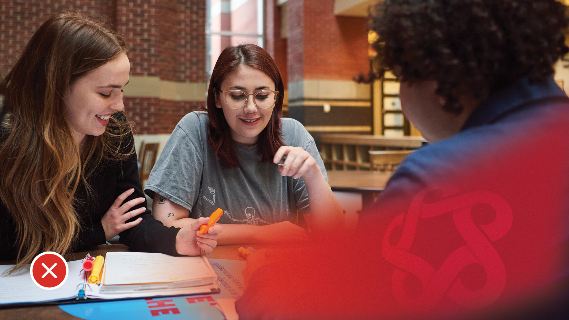 Three students engaged in a collaborative study session at a table, discussing notes and working on assignments. The image features a blurred logo in the corner.